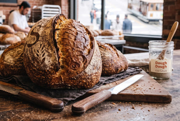 Authentic San Francisco sourdough loaves fresh from the oven with SF sourdough starter jar and cable car through the bakery window