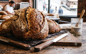Authentic San Francisco sourdough loaves fresh from the oven with SF sourdough starter jar and cable car through the bakery window